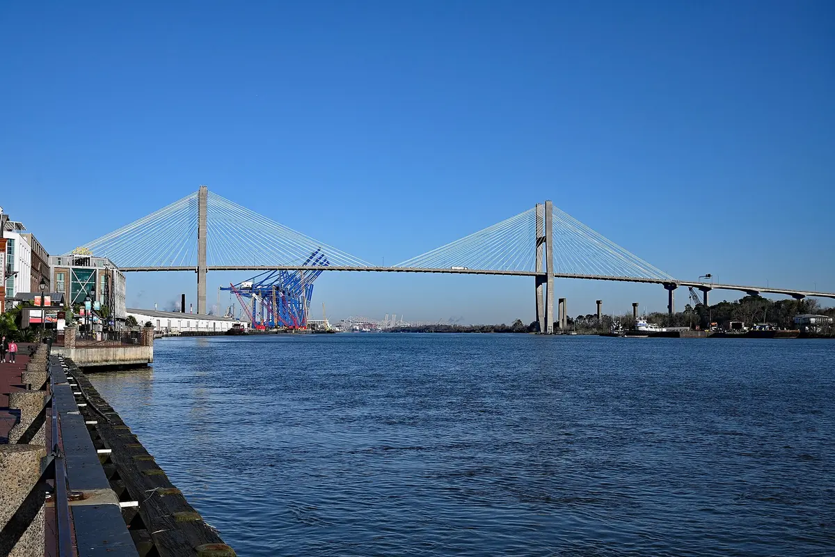 The cable-stayed Talmadge Memorial Bridge seen from the River Street promenade, with blue port cranes beneath its span.